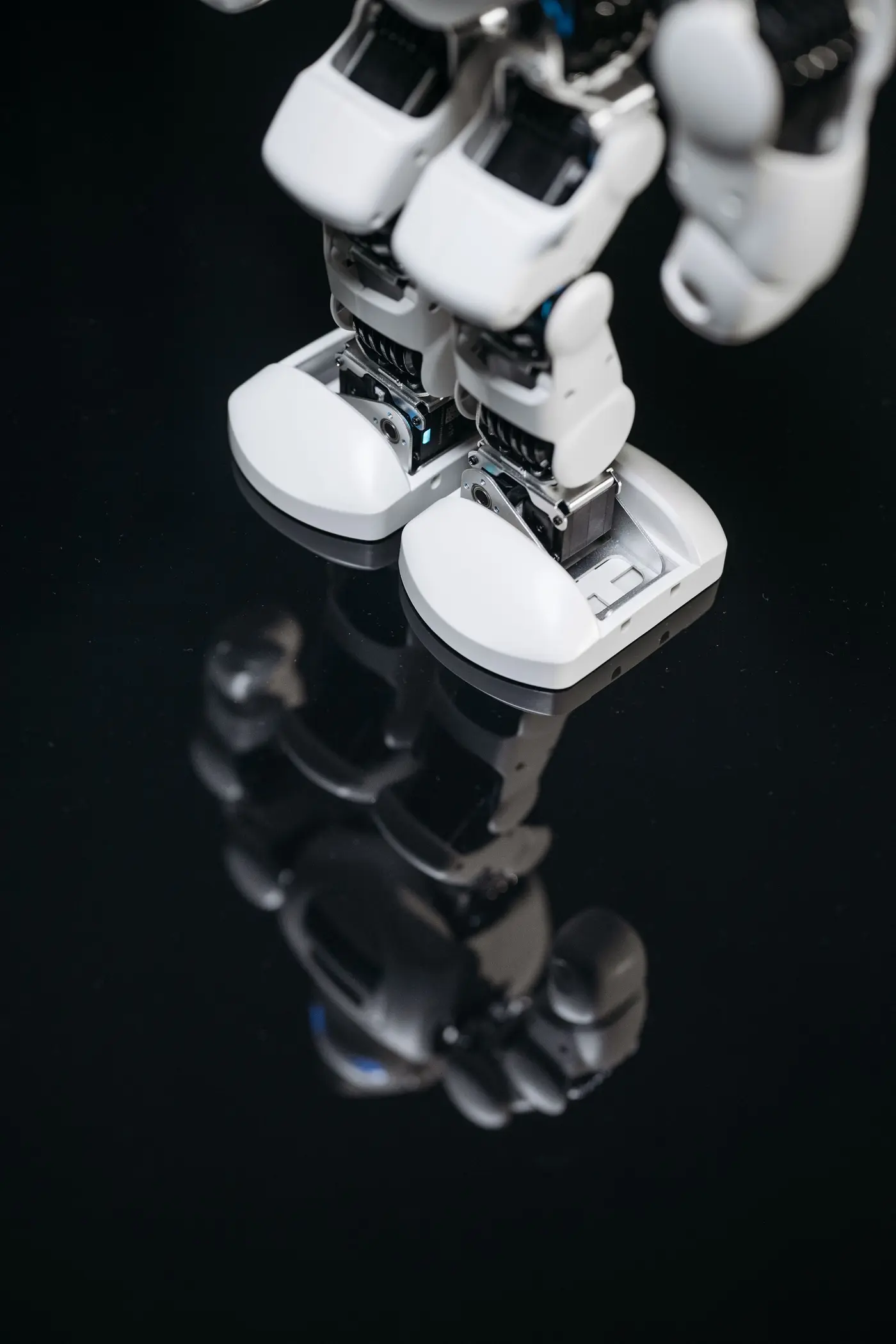 The feet of a humanoid robot reflected on a dark polished floor