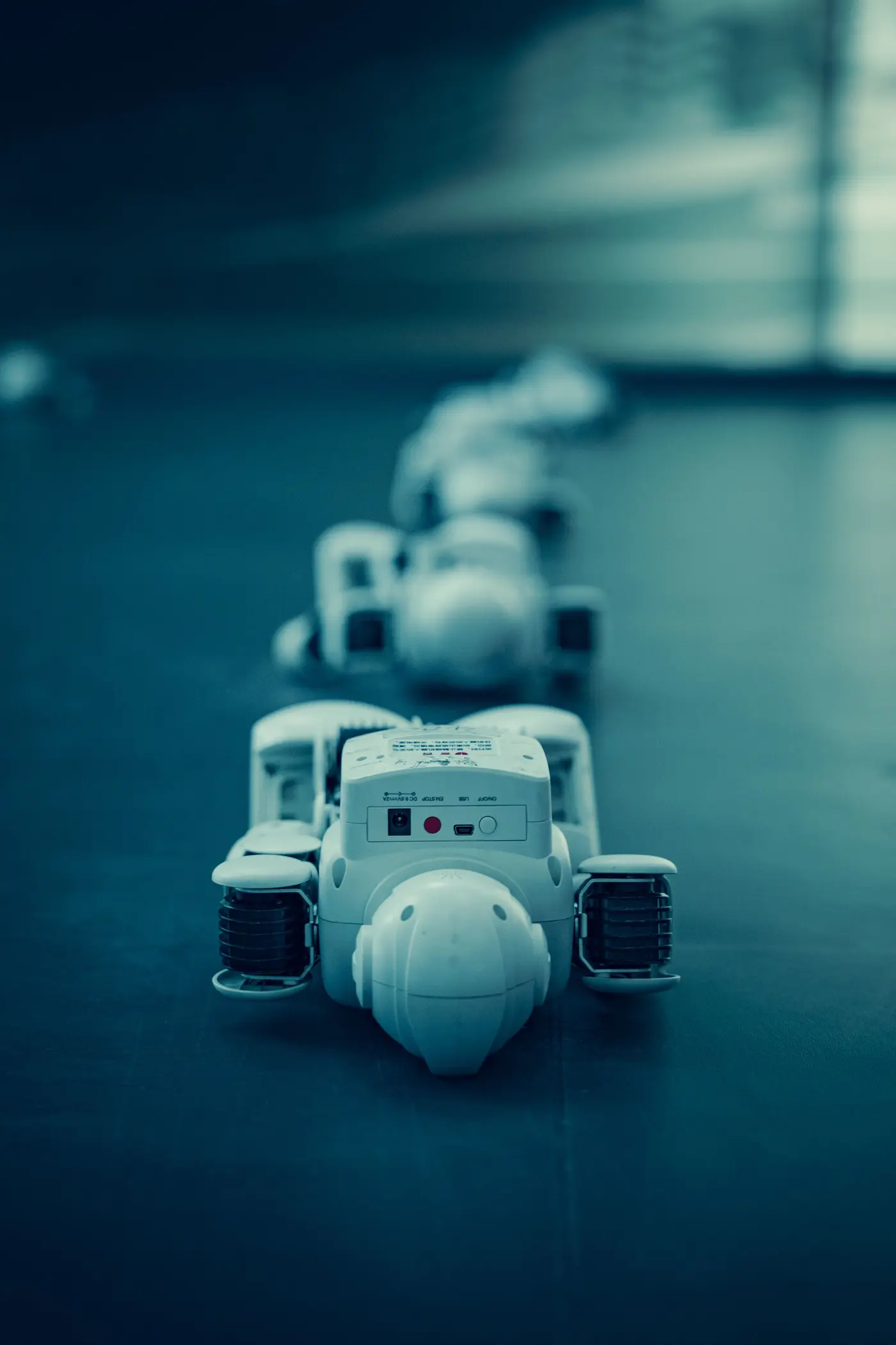 A row of small white humanoid robots lined up on a dark reflective surface